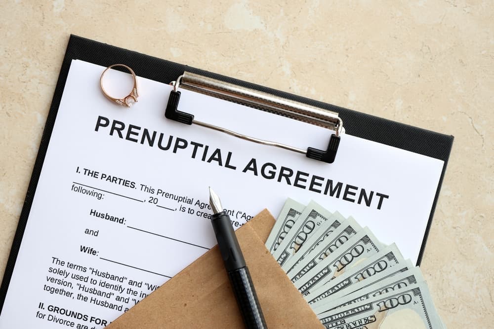 Prenuptial agreement and wedding ring on table. Premarital paperwork process