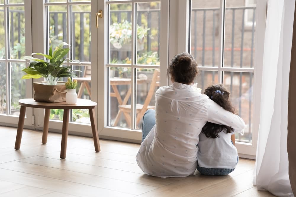 Black haired young mom and little daughter girl sitting on floor at home