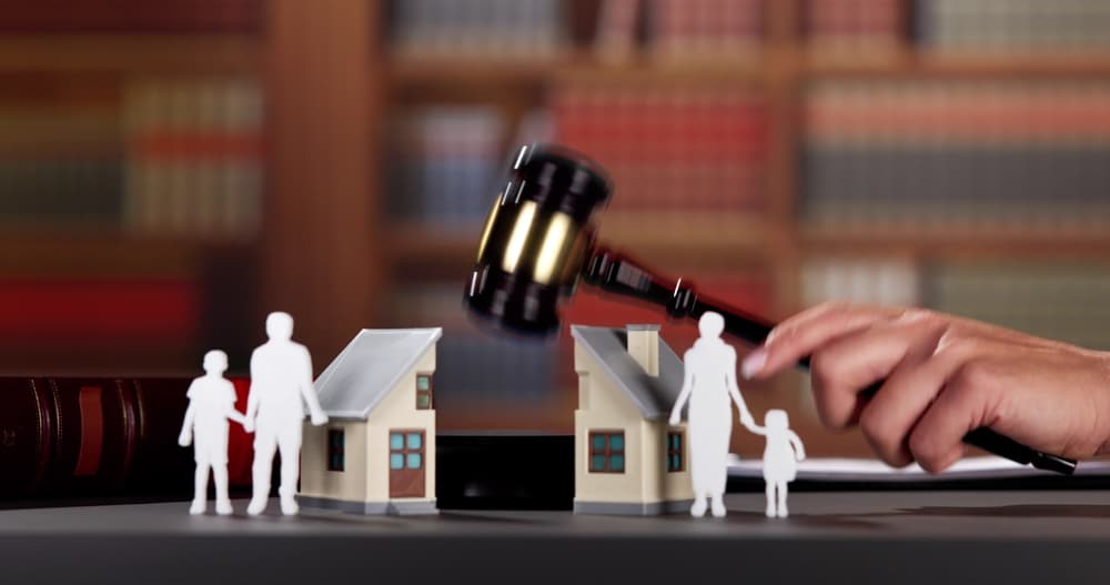 Law concept. Gavel, figures of parents with children and house on wooden table, closeup
