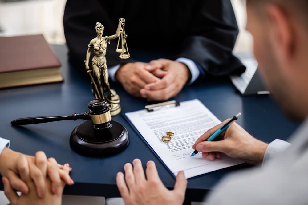 The lawyer, dressed professionally, guides them through the legal process, explaining the document. The couple, though solemn, is prepared to sign the divorce agreement, signaling the final stages of their separation.