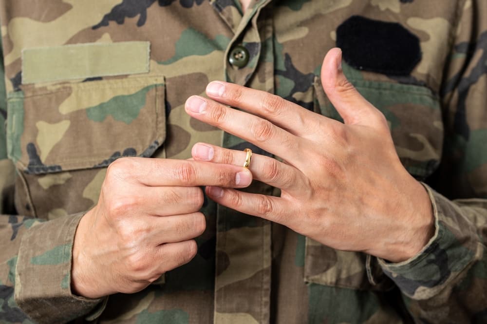 A soldier's hands as he prepares to remove his wedding ring.






