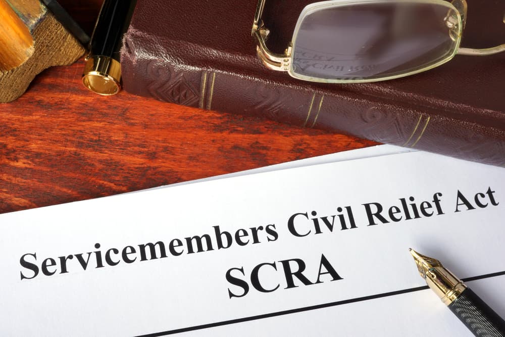 A close-up of a book titled "Servicemembers Civil Relief Act (SCRA)" lying on a desk, its pages open to reveal legal guidelines. The book symbolizes the protections offered to military personnel, detailing rights and provisions under the SCRA.